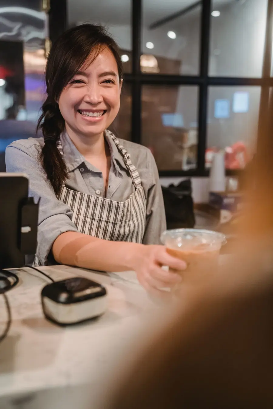 Kasir tersenyum melayani pelanggan di kafe